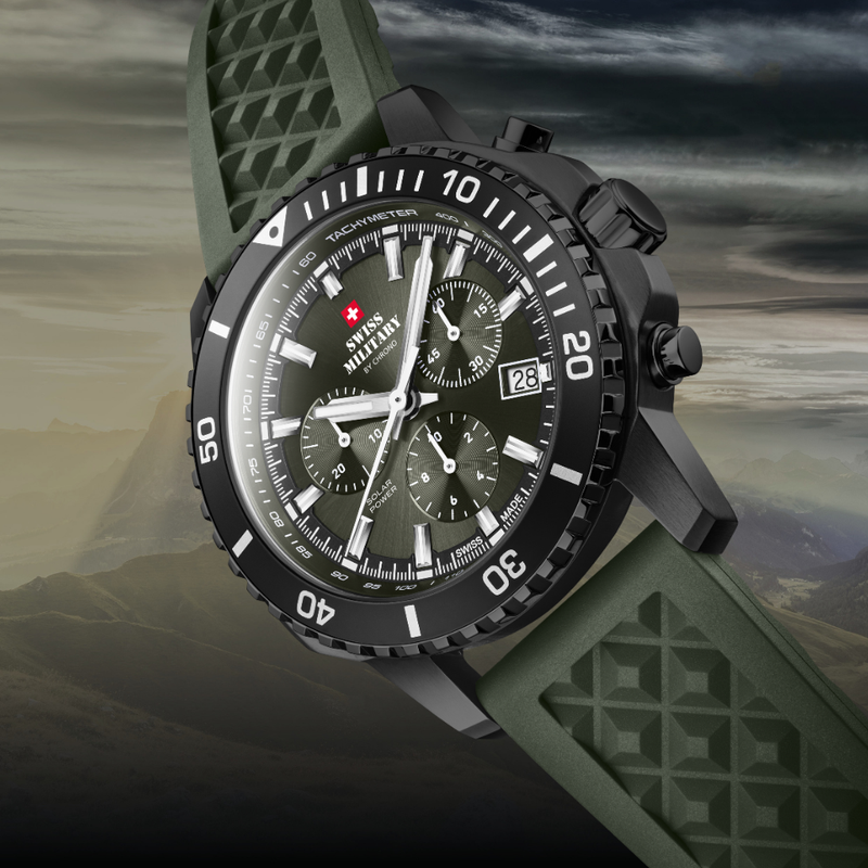 Rugged Solar chronograph watch SMS34113 with a black case, dark green dial, and  textured strap, shown diagonally against a dramatic cloudy sky and mountain backdrop.