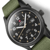 wiss Military SM34108.07 close-up showing matte black dial, luminous hands, beige military hours, sandblast finish case, and green canvas strap.